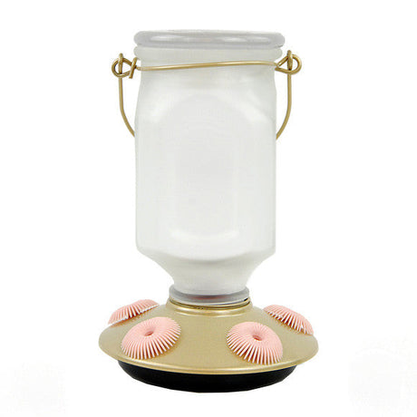 Product shot of a white glass hummingbird feeder with a gold base and pink perches featuring a wire carrying handle