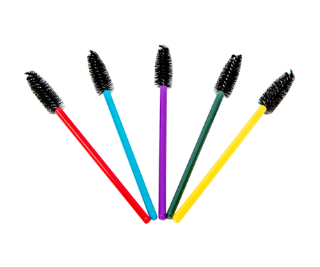 Product photography of five colorful mascara wands with black bristles against a white background red teal purple green and yellow handles are displayed in a fanned arrangement