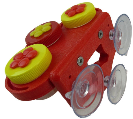 Plastic bird feeder with three red and yellow flower-shaped lids attached to a red base with four suction cups for window mounting