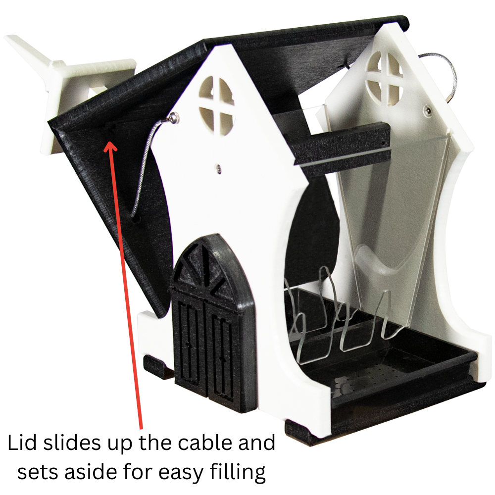 Plastic bird feeder with removable lid, featuring a house-like design with black trim, arched door, and cross-shaped window details showcasing easy filling mechanism