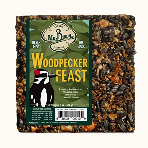 Mr. Bird's photograph of a Woodpecker Feast birdseed block shows a woodpecker illustration and a mix of black oil sunflower seeds, peanuts, and raisins against a green background