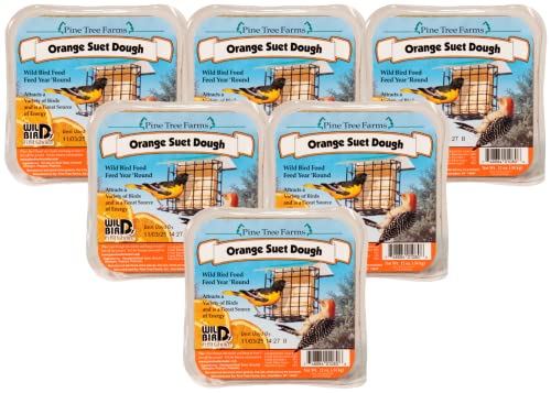 Pine Tree Farms product photography showing six packages of orange suet dough featuring a Baltimore oriole and a downy woodpecker near a bird feeder against a blue sky with vibrant orange and yellow hues