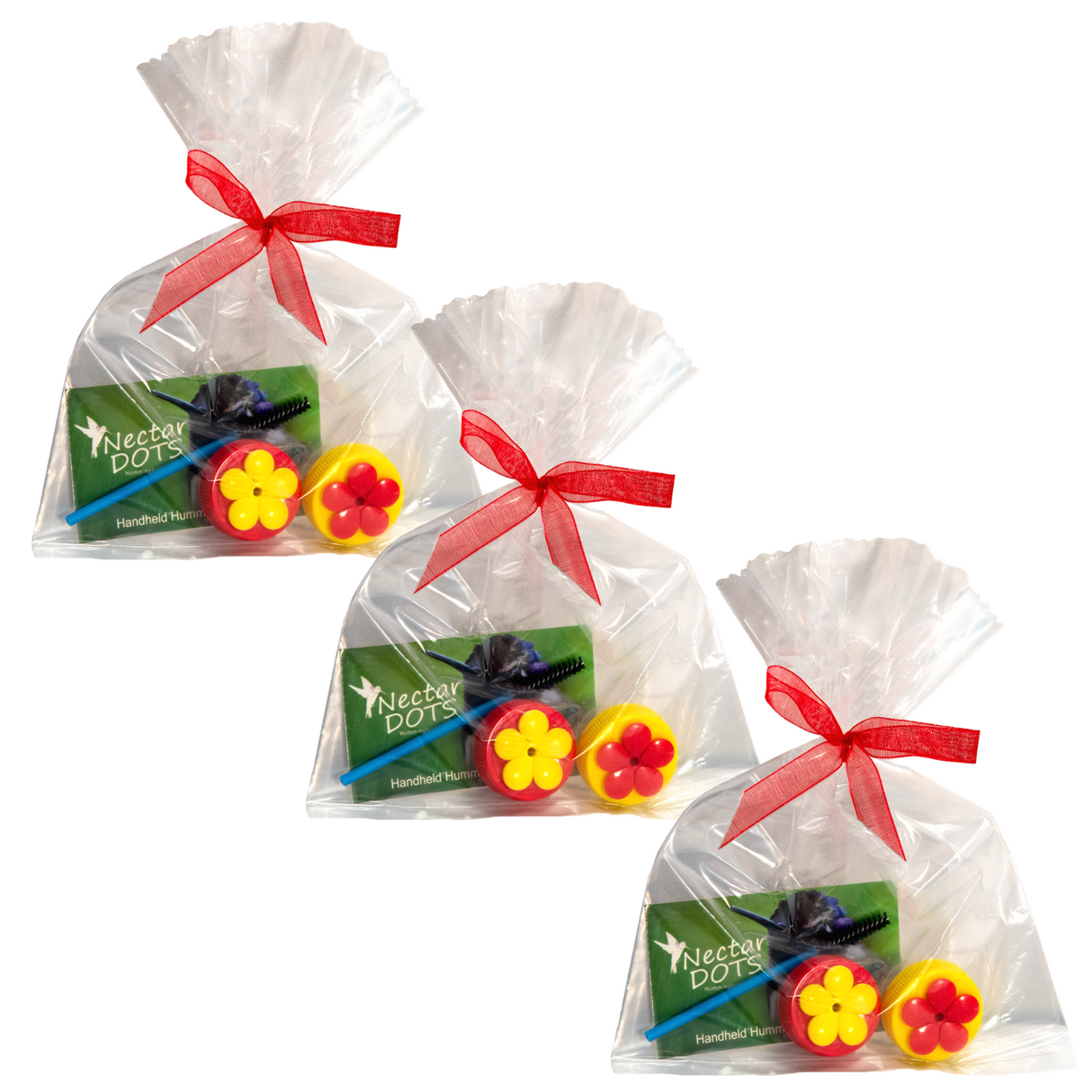 Product shot showing three cellophane bags tied with red ribbons each containing Nectar Dots hummingbird feeders two red and yellow flower-shaped caps a cleaning brush and informational card.