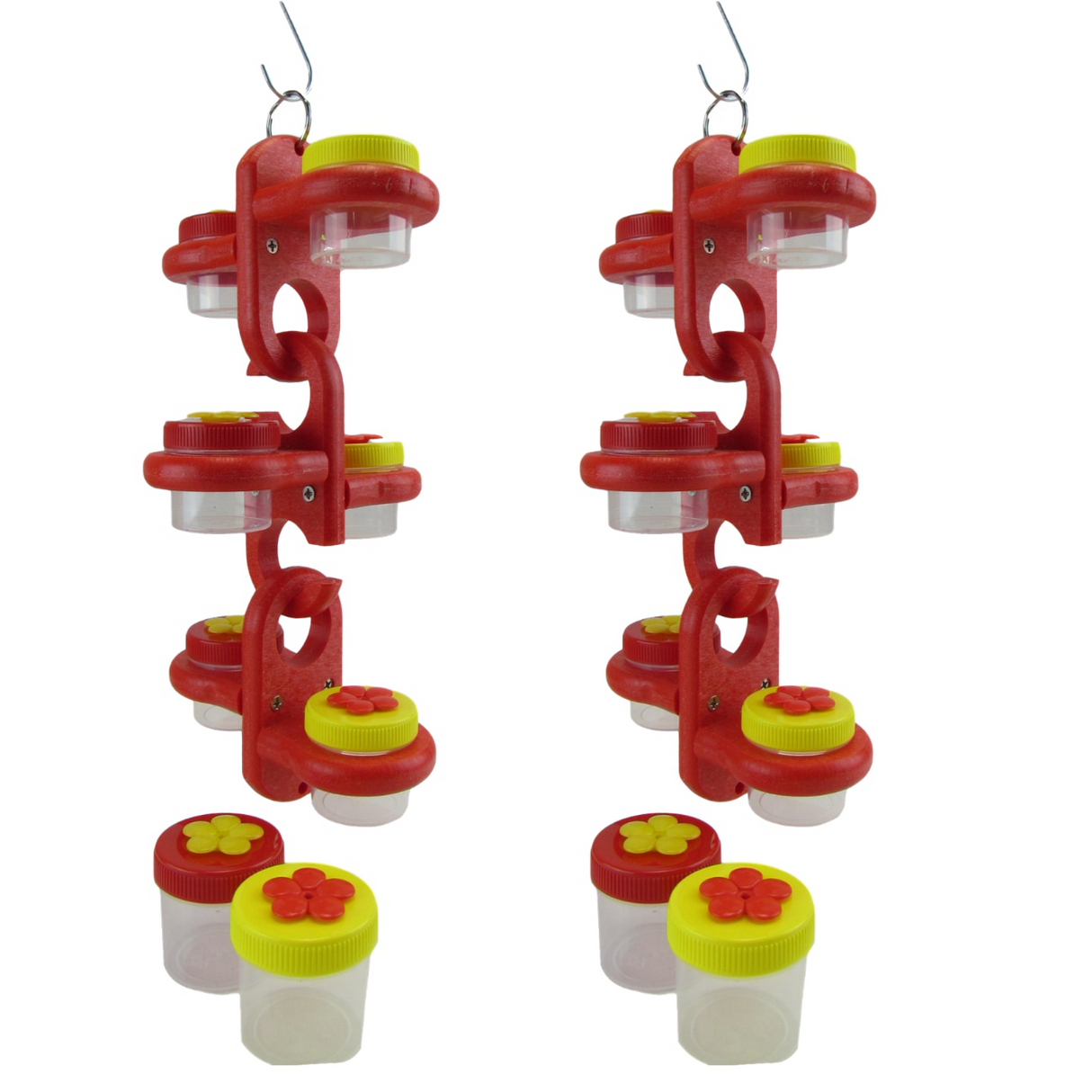 Two red plastic hummingbird feeders with multiple clear jars and yellow and red flower-shaped lids hanging against a white background