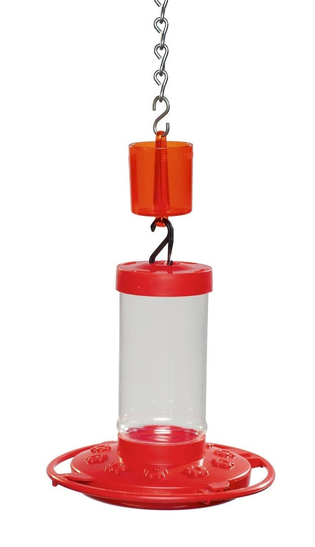Plastic hummingbird feeder with red base and orange reservoir featuring a clear cylinder a metal chain and a unique perch design