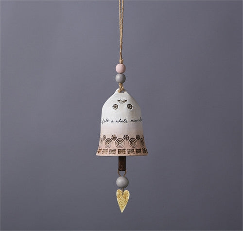 Ceramic bell by East of India featuring a pink and grey ombre design, a small butterfly, and a gold heart charm.