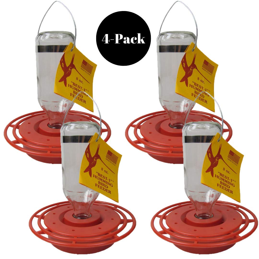 Product photo showing four red plastic Best-1 hummingbird feeders with clear glass bottles and yellow labels featuring a hummingbird graphic against a white background