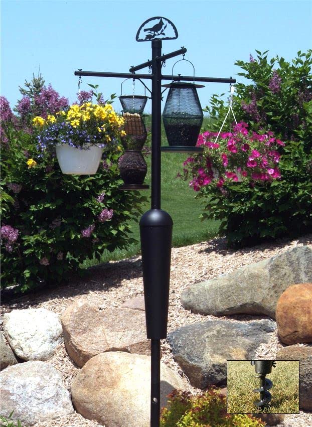 Squirrel Stopper Black Deluxe Squirrel Proof Pole System with Baffle in a garden, displaying feeders and plants.