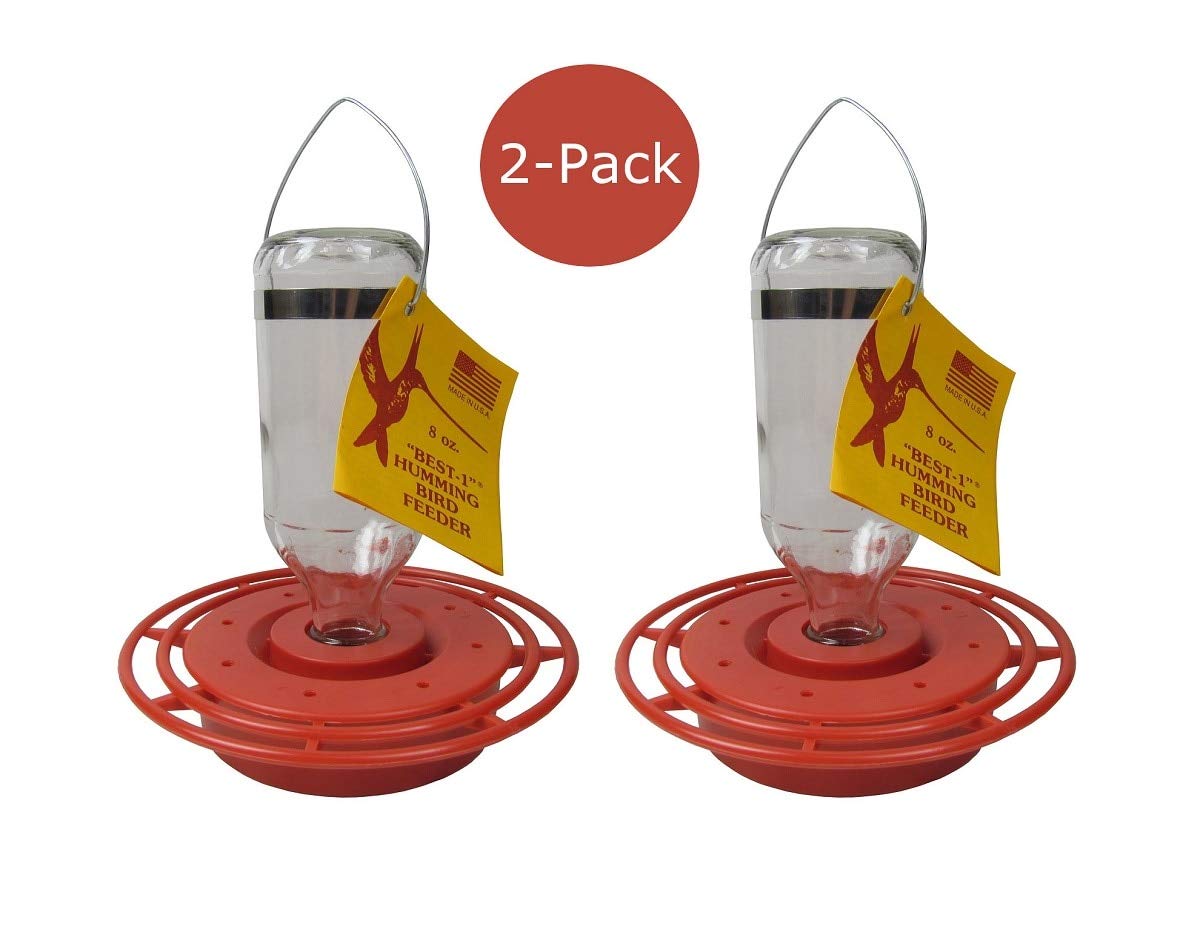 Product photo showing two Best-1 hummingbird feeders with red plastic bases and clear glass bottles featuring yellow labels and a hummingbird graphic against a white background
