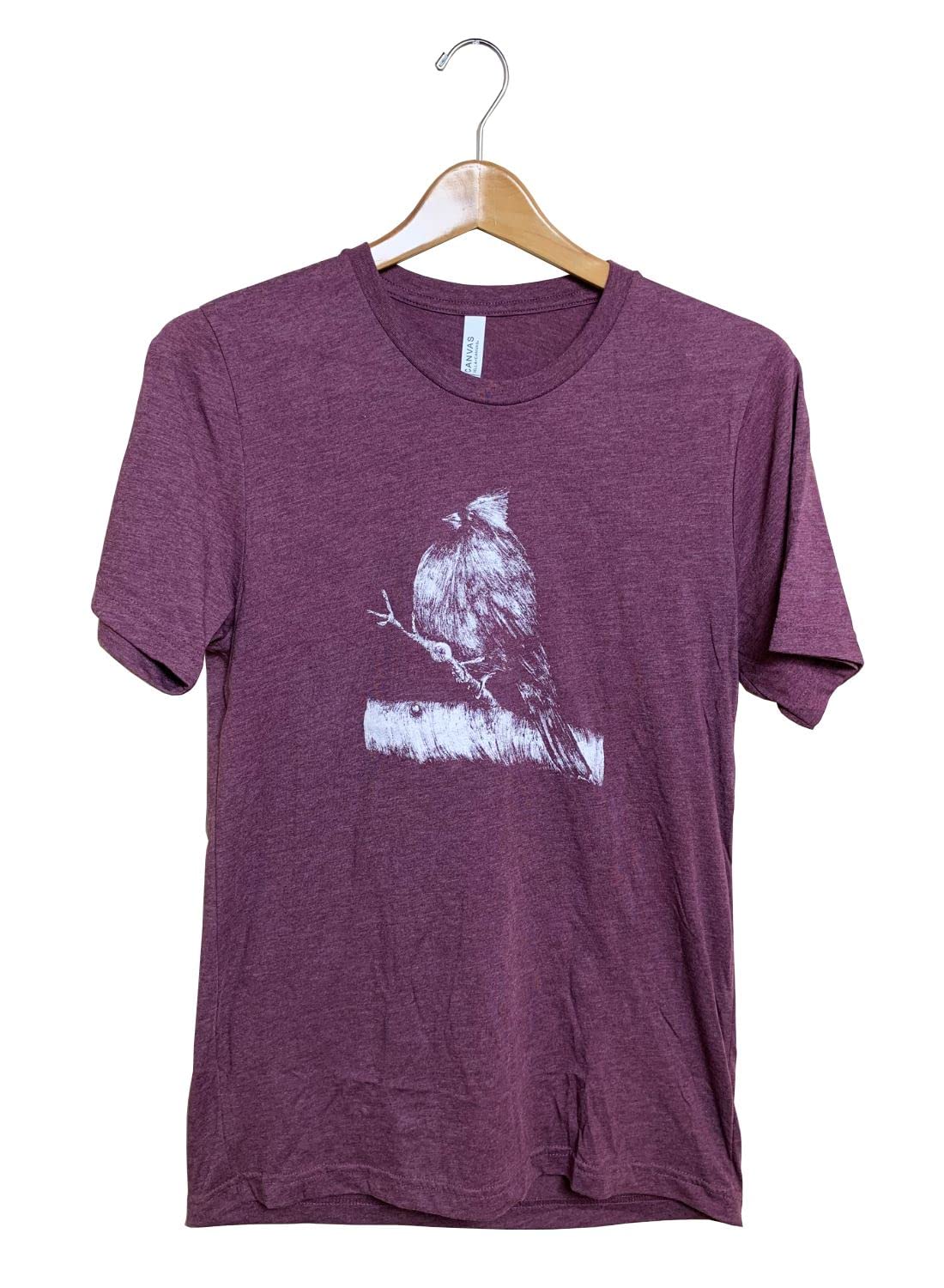 T-shirt featuring a white ink drawing of a cardinal perched on a branch with textured details and subtle shading on a maroon shirt