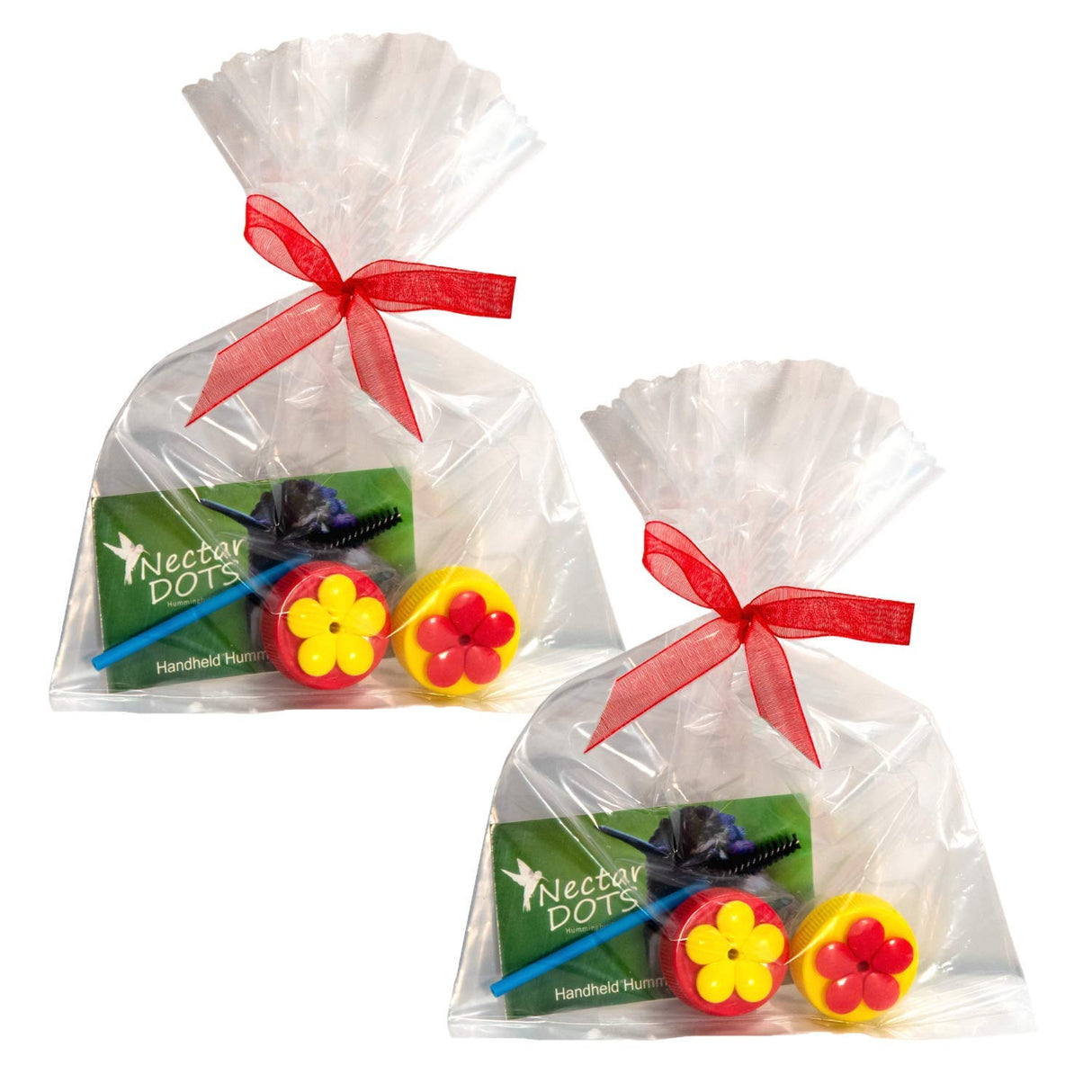 Product photography showing two cellophane bags tied with red ribbons each containing Nectar Dots hummingbird feeders yellow and red flower-shaped caps and a cleaning brush.
