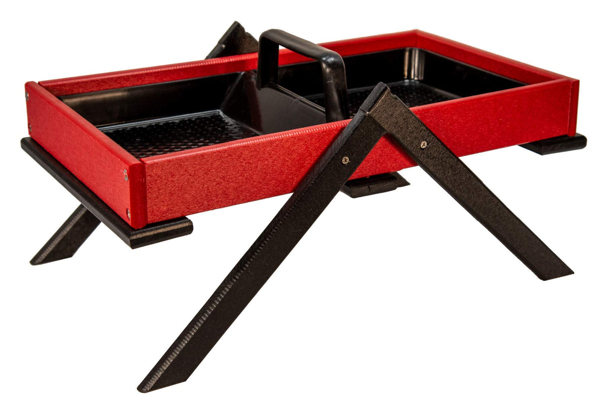 Product photography of a red and black bird feeder with a carrying handle and textured legs featuring a perforated black tray and visible screws