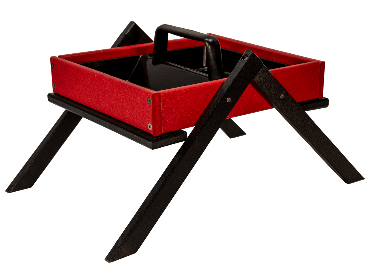 Product photography of a red and black recycled plastic bird feeder with a carrying handle and unique X-shaped stand featuring visible screws and textured surfaces