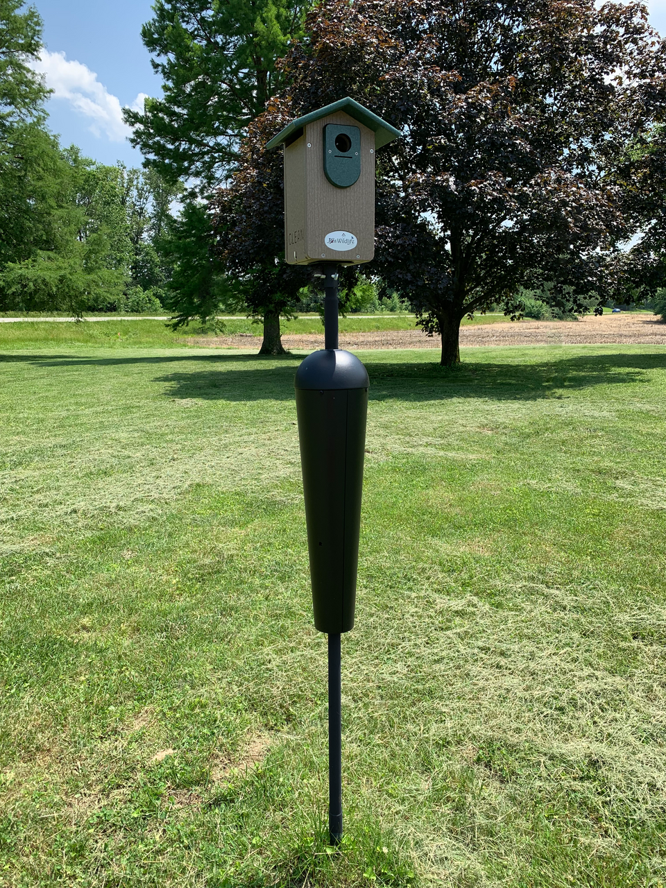 Squirrel Stopper Denali Squirrel Proof Mounting Pole System in a grassy field with birdhouse on top.