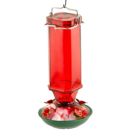 Glass hummingbird feeder with red glass reservoir and green base featuring artificial red and pink flowers and a silver metal hanger