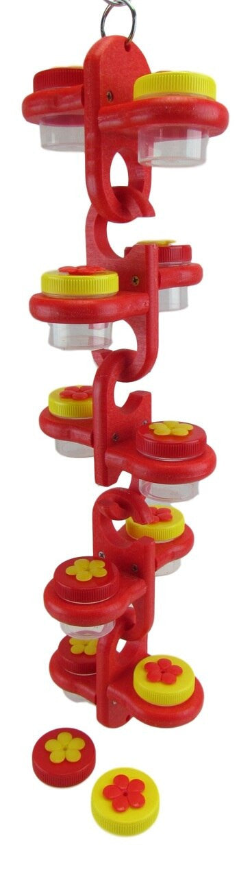 Plastic bird feeder toy with red and yellow flower-shaped lids and clear containers hanging from a red chain