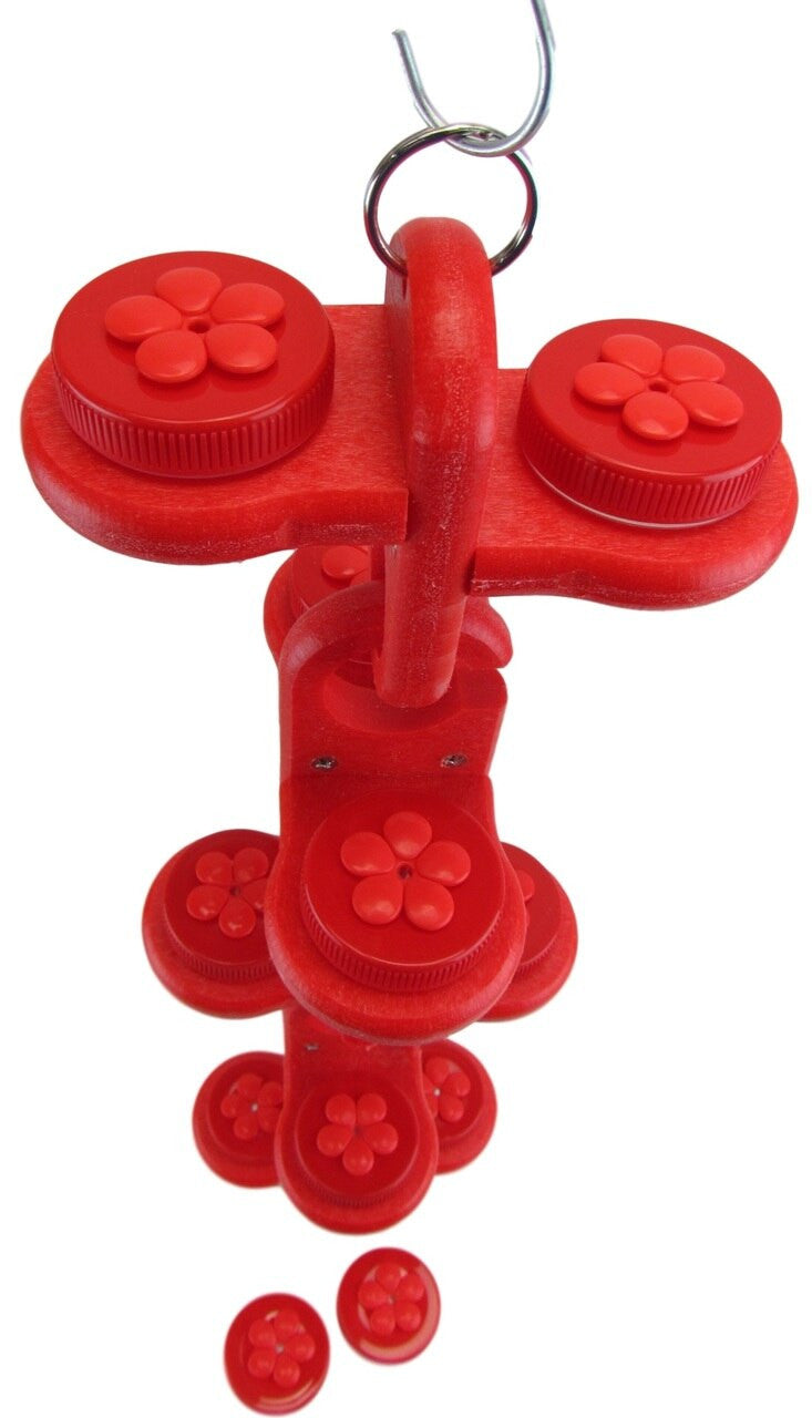 Plastic red bird feeder toy with flower-shaped details hanging from a metal hook showing vibrant red color and multiple levels
