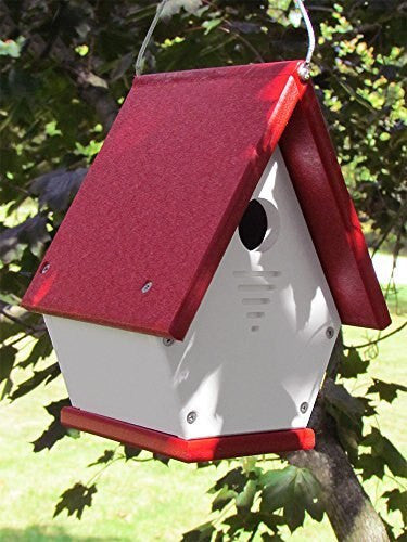 Recycled plastic birdhouse hanging from a tree branch featuring a vibrant red roof white body and a small ventilation hole showcasing a charming red base and visible screws