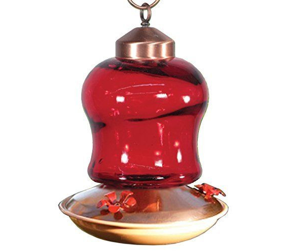 Glass hummingbird feeder with copper accents showing a vibrant red glass reservoir and red flower-shaped feeding ports against a white background