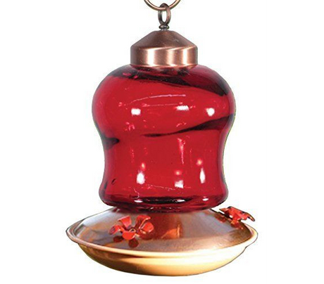 Glass hummingbird feeder with copper accents showing a vibrant red glass reservoir and red flower-shaped feeding ports against a white background
