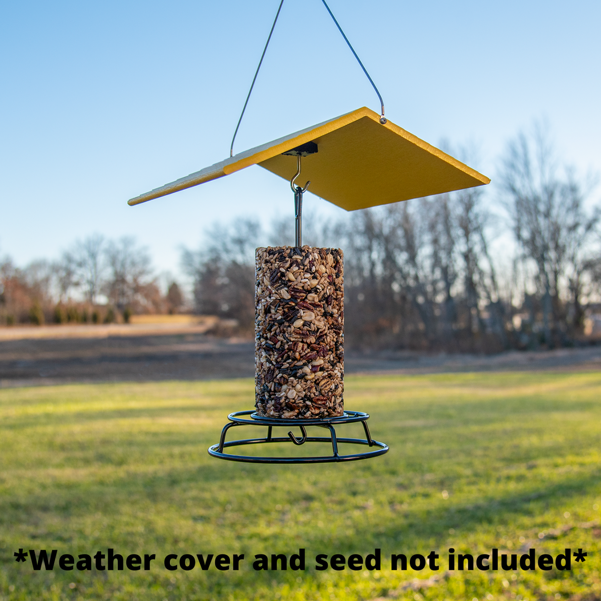 JCS Wildlife Bird Seed Cylinder Feeder hanging in yard, made of heavy metal, featuring an open top design for easy use.