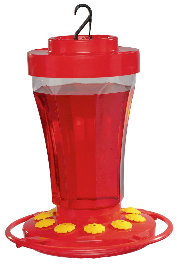 Plastic hummingbird feeder with bright red body clear reservoir and yellow perches filled with red nectar hanging from a black hook