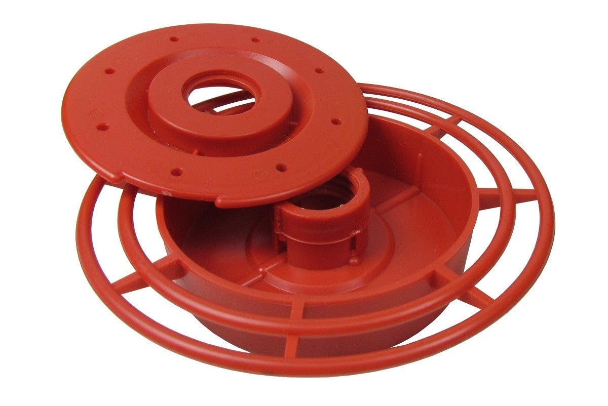 Plastic hummingbird feeder disassembled showing vibrant red base, removable top, and a circular perch with multiple bars
