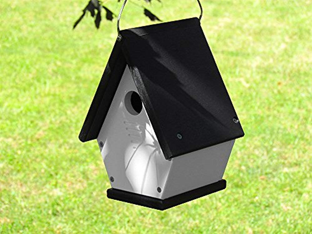 Recycled plastic birdhouse hanging outdoors showing a black roof white body and small entrance hole