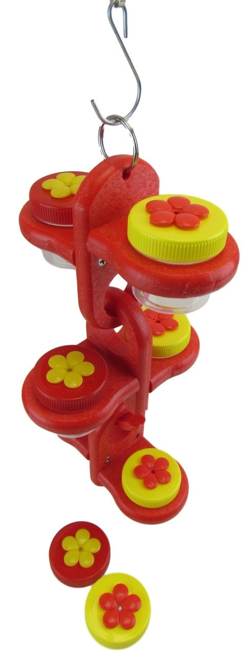 Plastic bird feeder toy with red and yellow flower accents hanging from a metal hook featuring multiple small clear containers