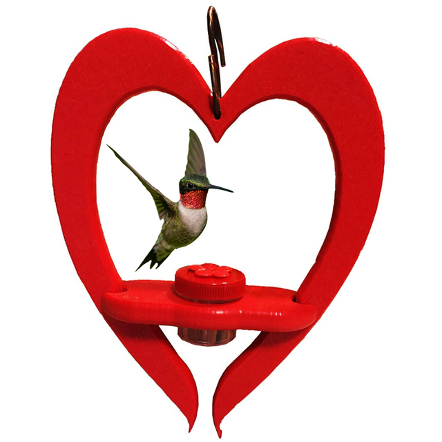 Handmade wooden hummingbird feeder shaped like a vibrant red heart featuring a ruby-throated hummingbird near a red flower-shaped cap and a small copper hook for hanging