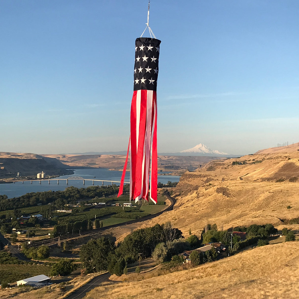 In the Breeze U.S. Stars and Stripes Embroidered 40" Windsock fluttering in the wind over scenic landscape.