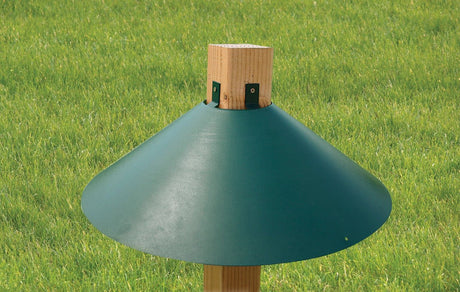 Audubon Woodlink 22-inch green metal squirrel baffle on post, squirrel proof bird feeder accessory in grassy outdoor setting.