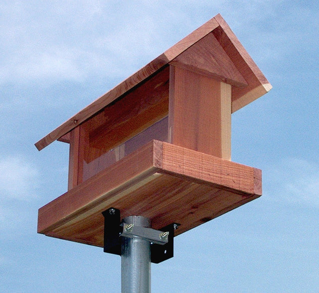 Wooden bird feeder mounted using Heritage Farms Universal Mounting Bracket on a metal pole against a blue sky.