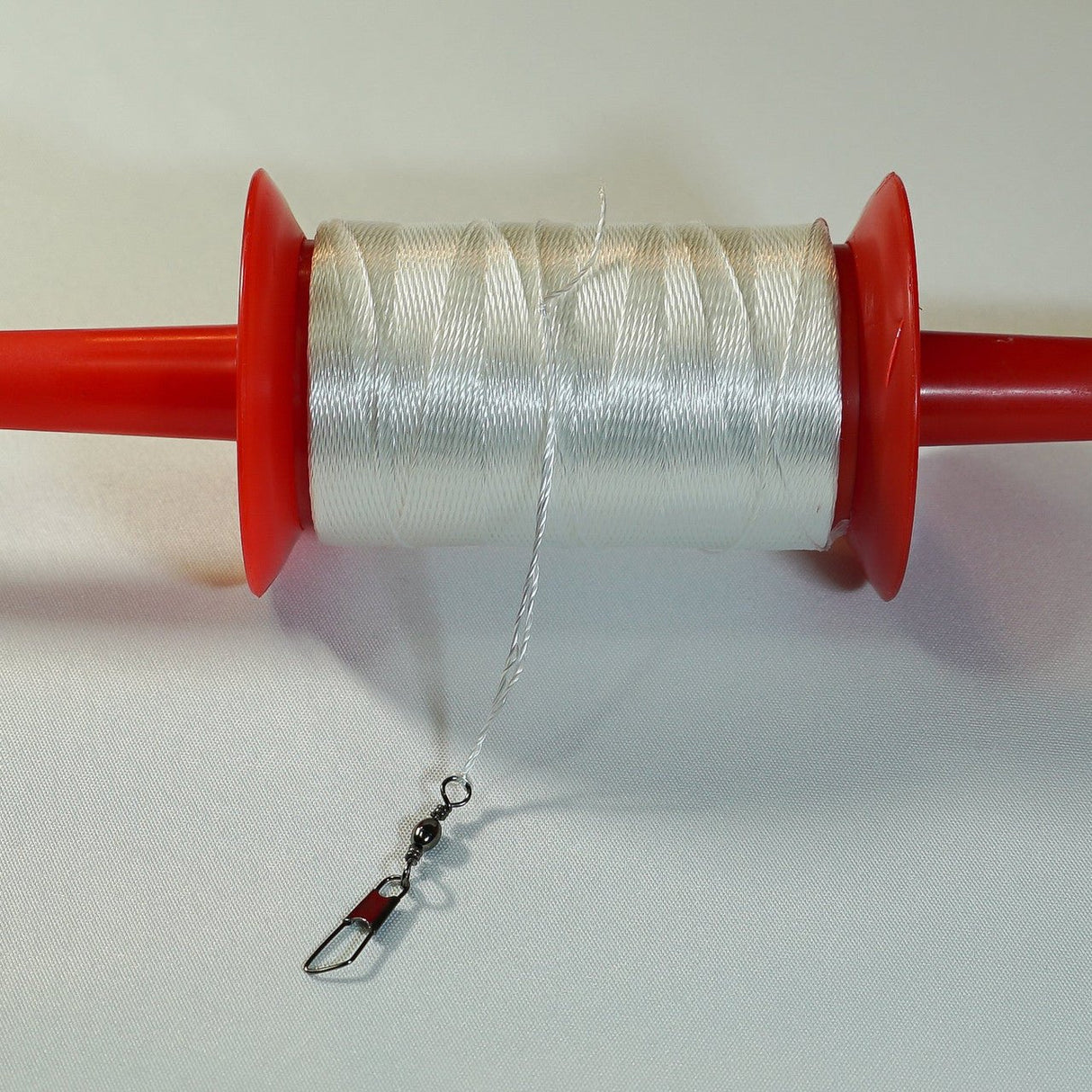 Red spool with white 30 LB x 500' twisted kite line featuring an attached snap swivel for easy kite connectivity.