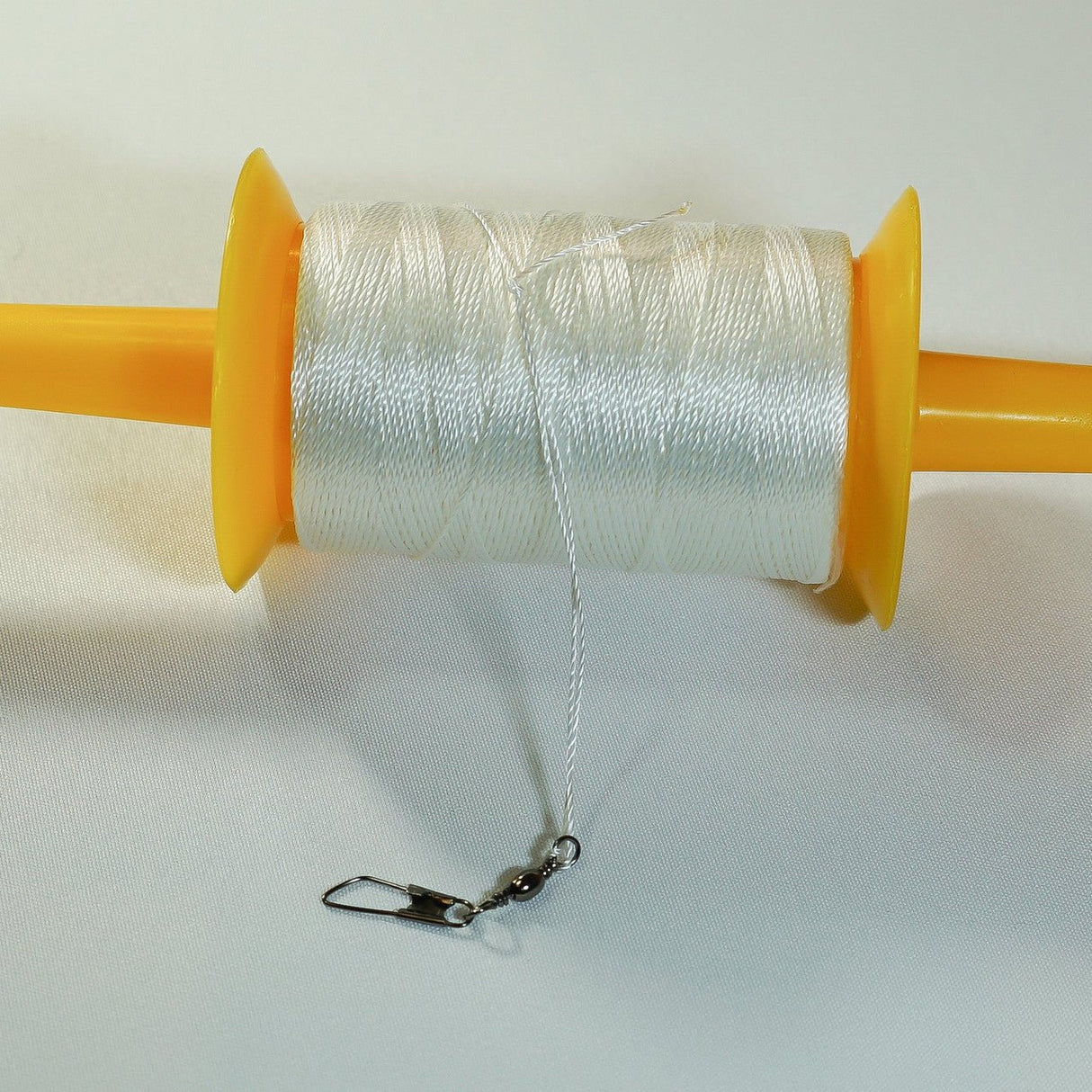 In The Breeze 50 LB x 500' Twisted Kite Line on durable yellow plastic spool with snap swivel attached.