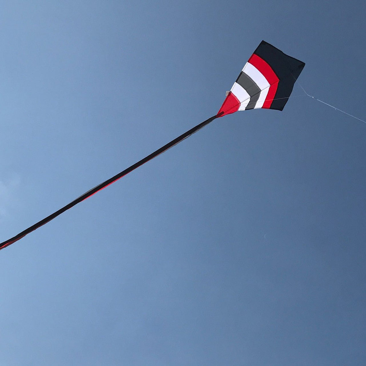 Blazer Arch 27" Diamond Kite with red, black, and white design flying in a clear blue sky