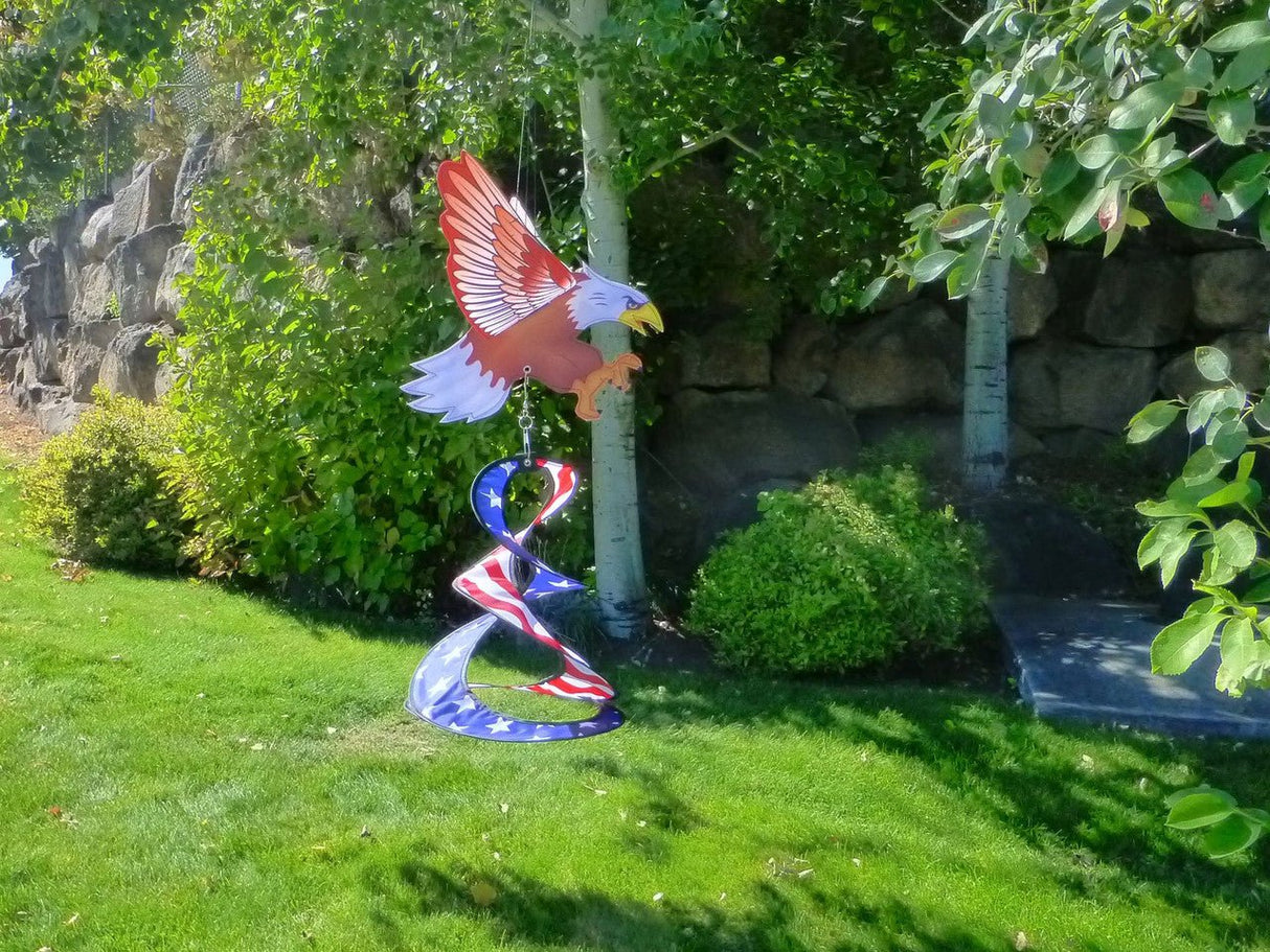 Double Patriotic Eagle Wind Spinner in a garden, spinning under a 3D Bald Eagle, showcasing red, white, and blue colors.