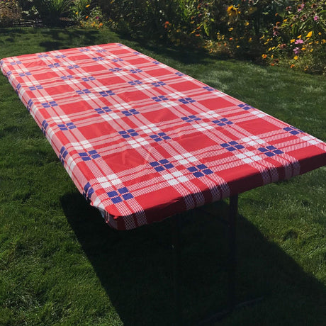 In the Breeze Plaid 6 Foot Fitted Tablecloth on outdoor table, vibrant red and blue plaid pattern, perfect for picnics and events