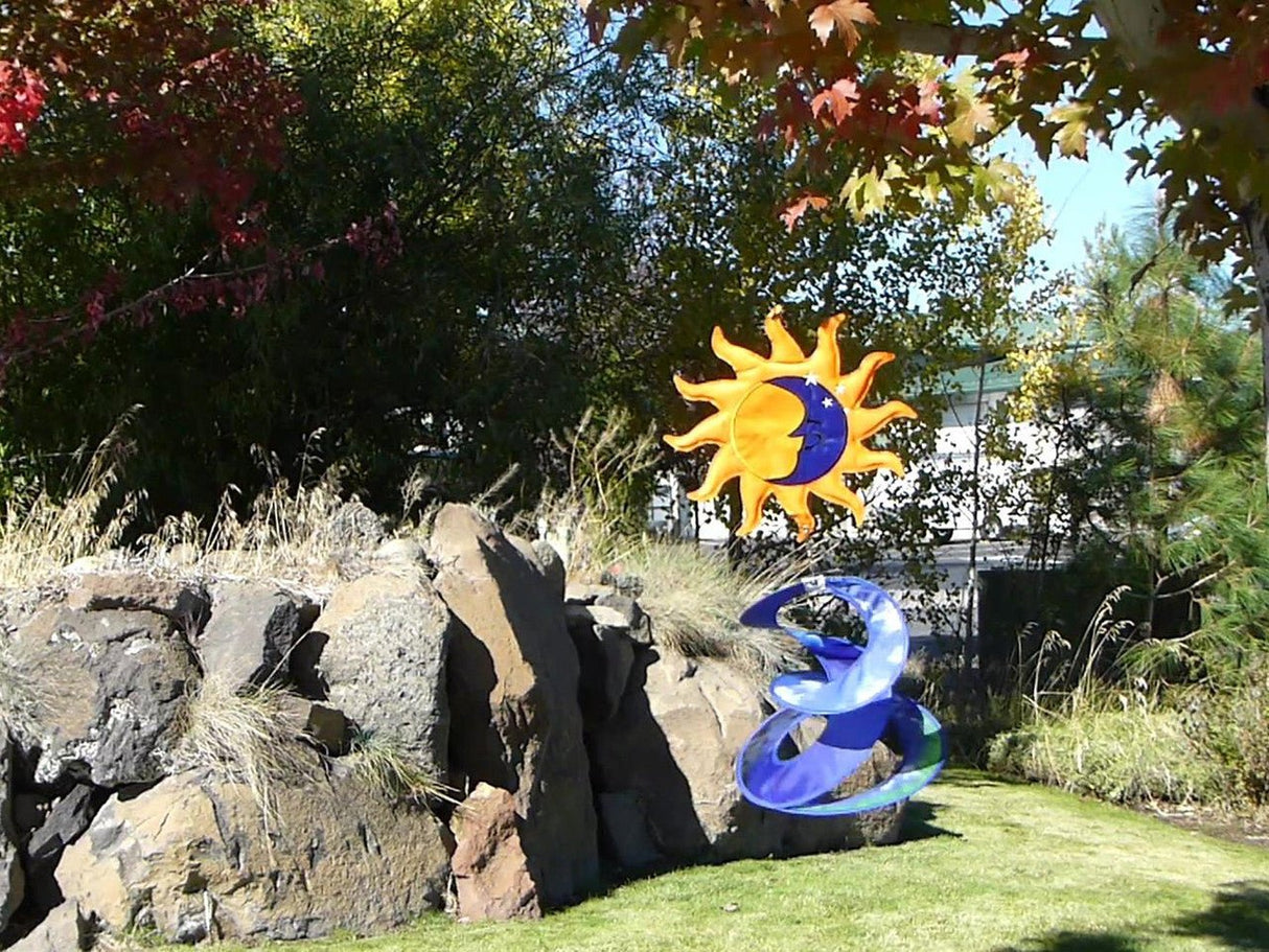In the Breeze Sun and Moon Wind Spinner with detailed dual spinners spinning fluidly in a garden, creating a soothing visual effect