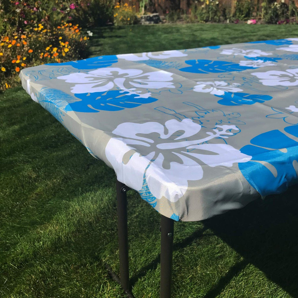 Tropical 6-foot fitted tablecloth with blue and white floral design on outdoor table, perfect for picnics, camping, or events