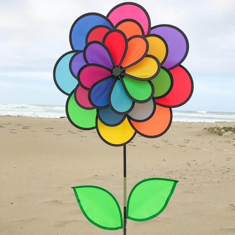In The Breeze 24-Petal Flower Triple Wheel Spinner with Leaves in rainbow colors, spinning on the beach.