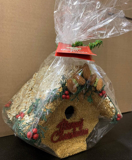 Festive Mr. Bird juniper casita wren house covered in bird seed, decorated with a Merry Christmas sign, almonds, millet, safflower, and kiwi.