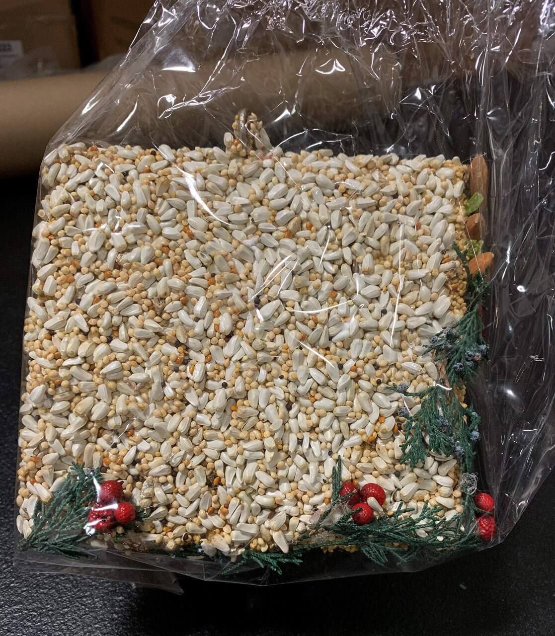 Festive Christmas Wren house covered in bird seed blend including millet, safflower, almonds, and decorated with juniper and berry accents.
