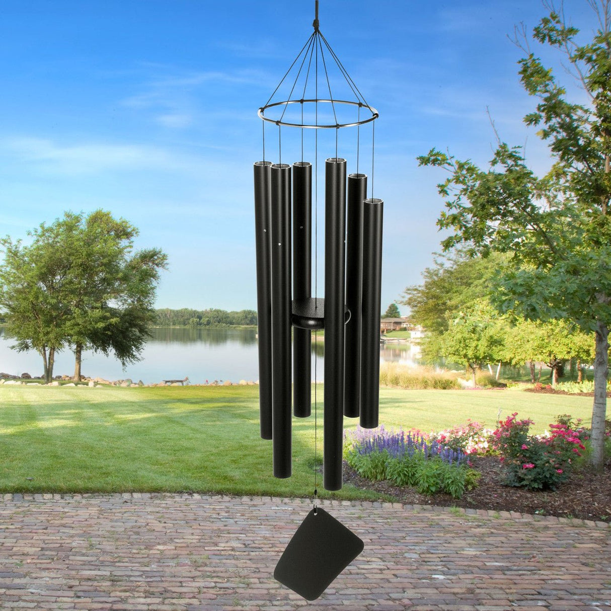 Balinese Mezzo Wind Chime by Music of the Spheres hanging in a scenic garden near a lake.