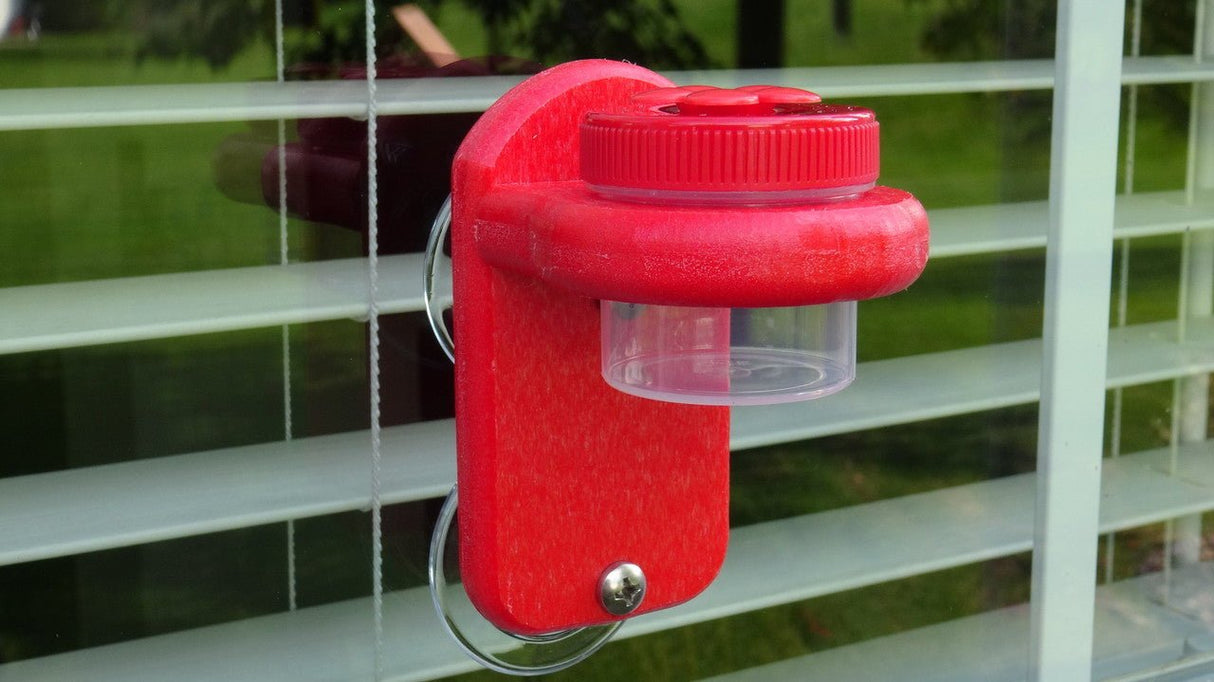 Nectar DOTS Window Hummingbird Feeder with red flowers attached to a window, showcasing easy installation and small design.