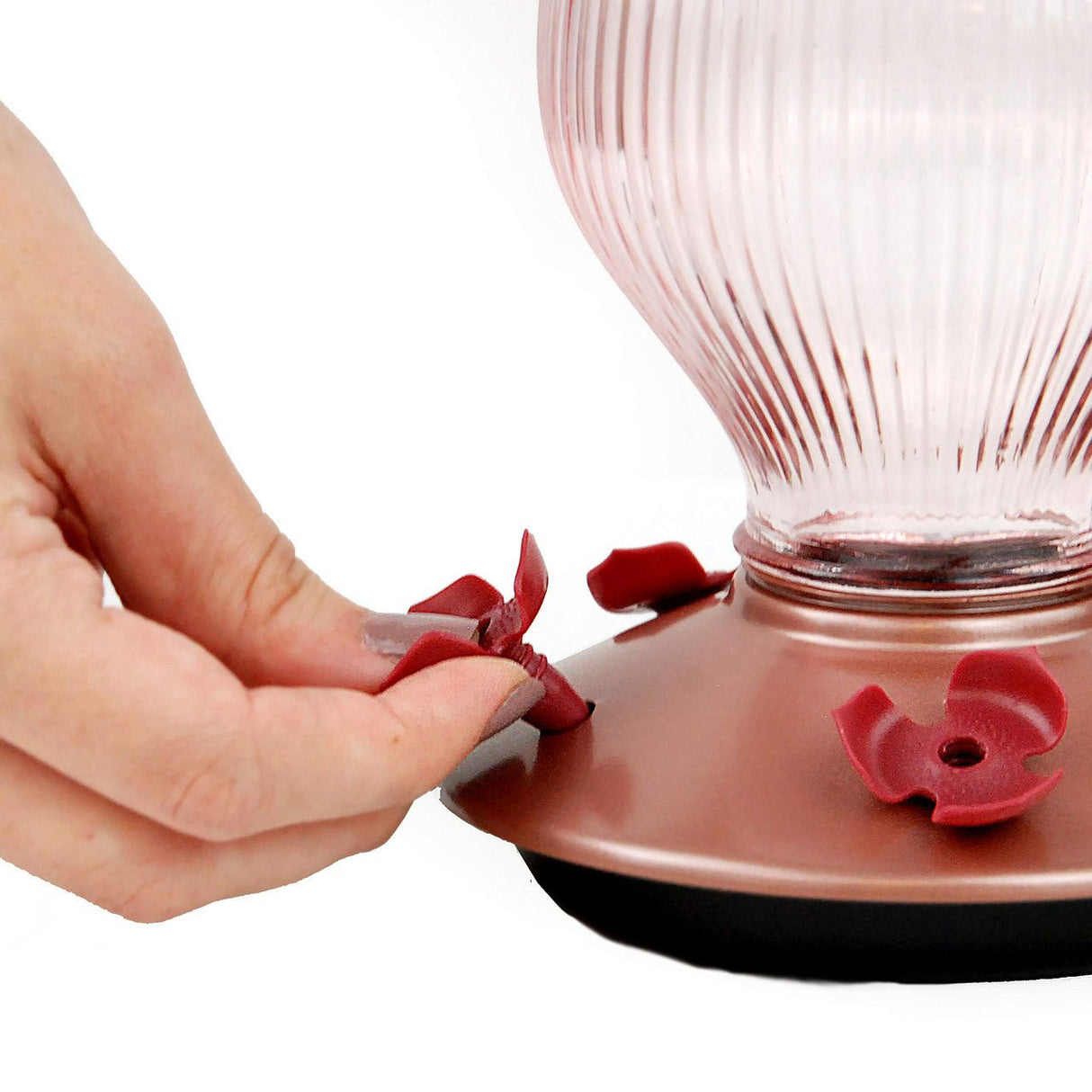 Hand removing flower-shaped feeding port from Perky-Pet Rose Gold Top-Fill Glass Hummingbird Feeder