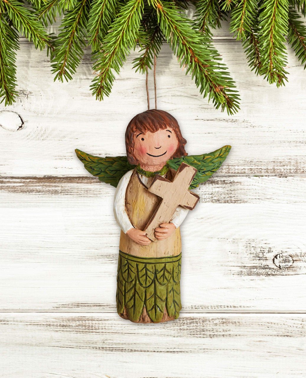 Studio M Choose Faith Angel Ornament featuring a smiling angel holding a cross, surrounded by evergreen branches.