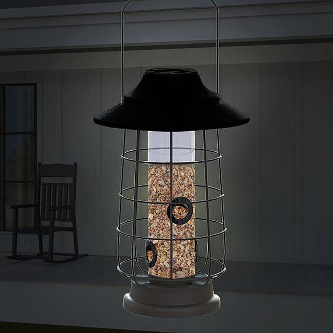 Woodlink Modern Farmhouse Gaslight Solar Light Coppertop Seed Feeder at night, filled with seeds for backyard birds.