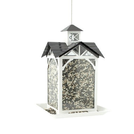 Woodlink Modern Farmhouse Metal and Glass Stable Feeder White with seeds in clear reservoir, rustic design for bird feeding.