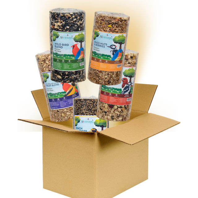 Jo's Wildlife product photography showing a cardboard box overflowing with premium birdseed blends including Wild Bird Blend, Bugs Nuts & Berries, and Finch Favorite featuring colorful bird illustrations and detailed ingredient labels
